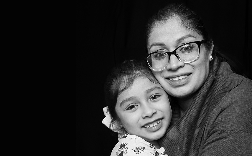 A black and white photo of a mother hugging her daughter, both smiling.