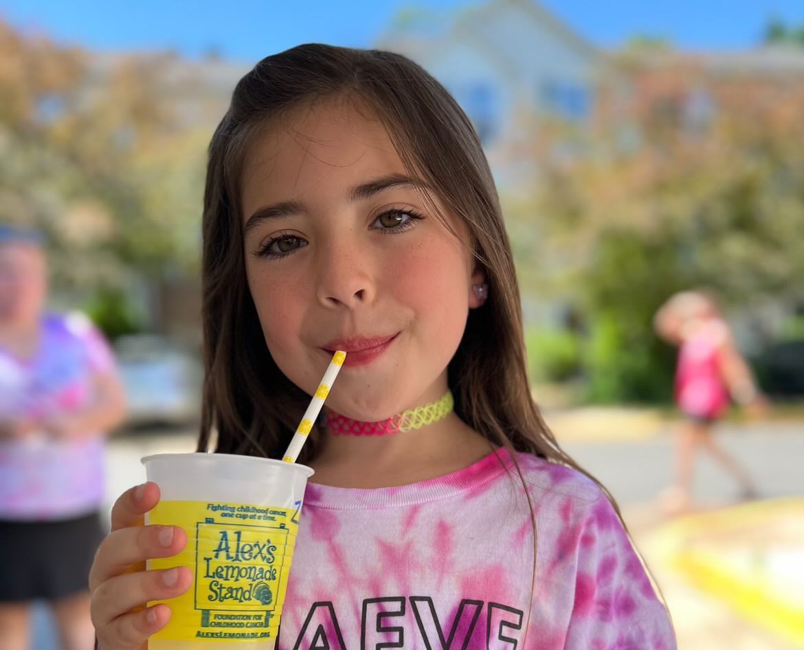 Girl holding a lemonade at a Lemonade Stand